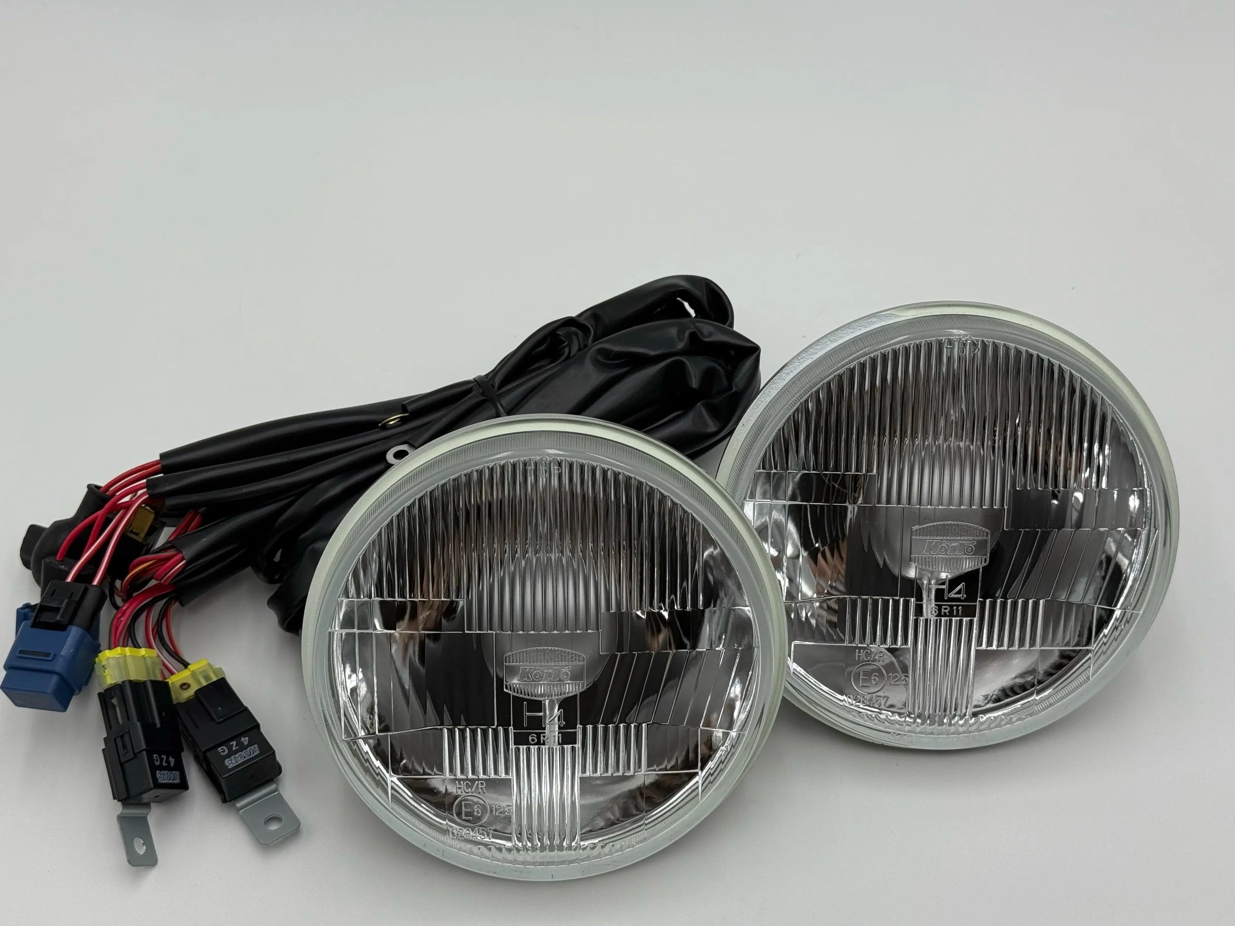 Two round 7in headlights for BMW 2002 with wiring harness on a white background