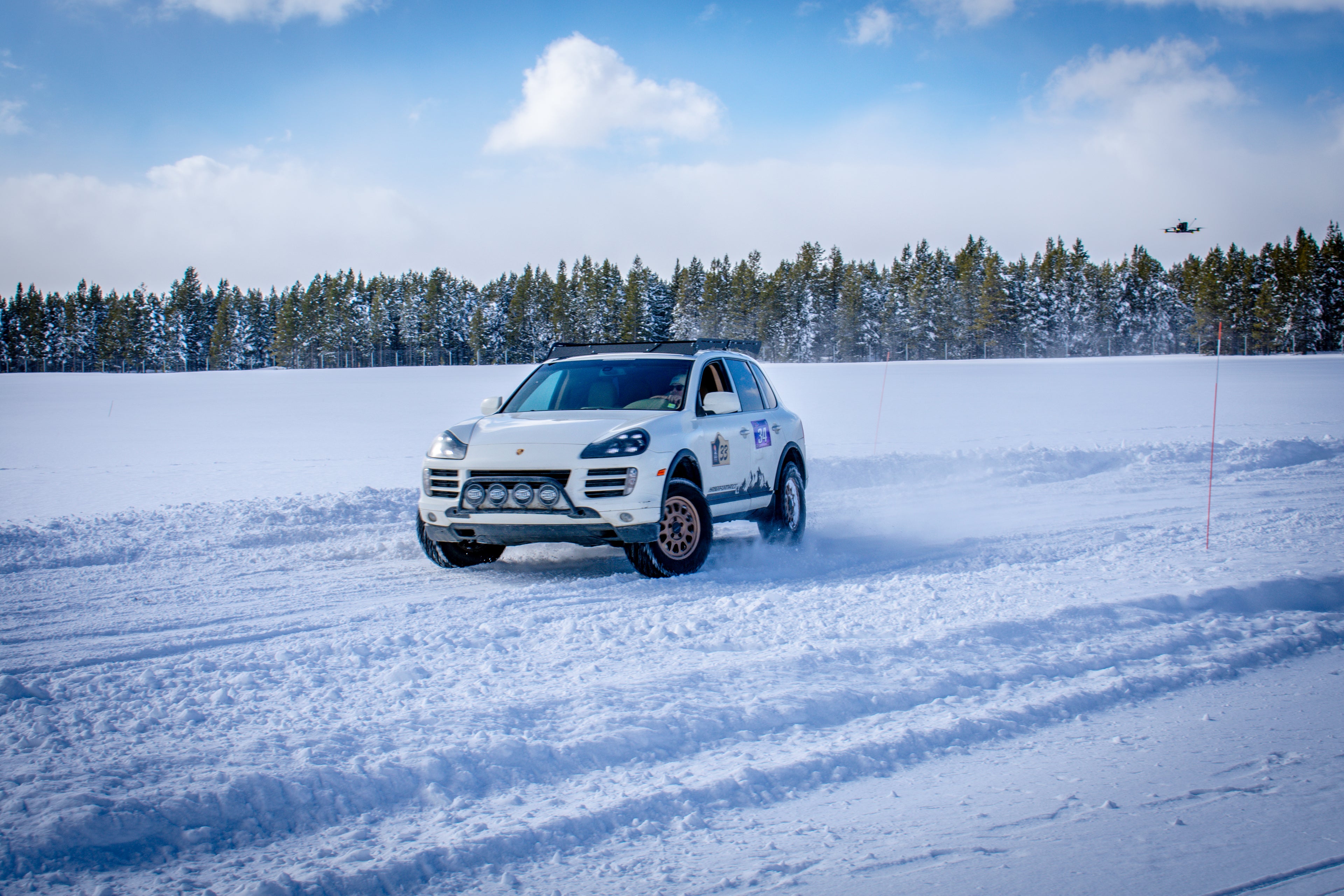 White SUV driving on a snow-covered track with trees in the background