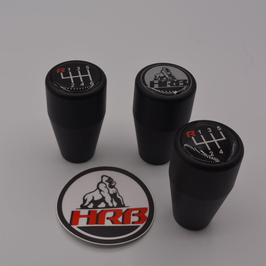 Four black HRB gear/shift knobs with logos and a circular HRB logo badge on a gray background.